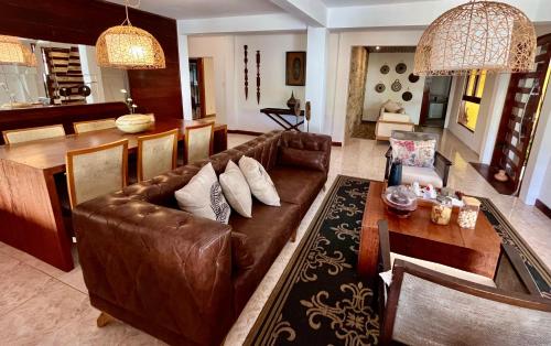 a living room with a brown leather couch and a table at Villa Biju in Jericoacoara