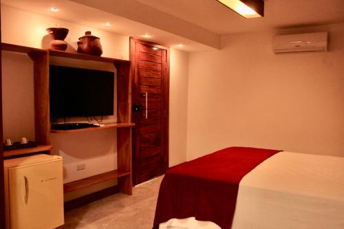 a bedroom with a bed and a flat screen tv at Villa Biju in Jericoacoara