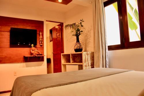 a bedroom with a bed and a window and a tv at Villa Biju in Jericoacoara