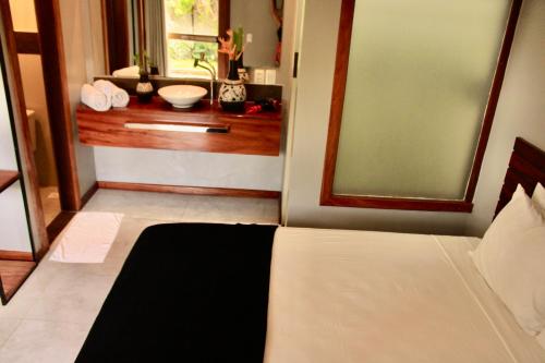 a bedroom with a bed and a bathroom with a sink at Villa Biju in Jericoacoara