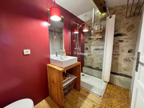 La salle de bains est pourvue de murs rouges, d'un lavabo et d'une douche. dans l'établissement La Maison du Fenil de Tende Vallee des Merveilles, à Tende
