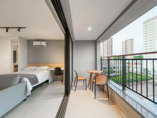 a bedroom with a bed and a balcony with a table and chairs at Vista XV by Housi in Campo Grande