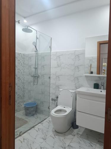 a white bathroom with a toilet and a shower at plage Taït club omeGa in Andalouciene