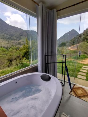 a bath tub in a room with a large window at Reserva das Oliveiras in Nova Friburgo