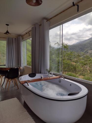 a bath tub in a room with a large window at Reserva das Oliveiras in Nova Friburgo