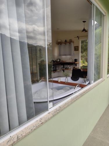a window with a view of a tub in a room at Reserva das Oliveiras in Nova Friburgo