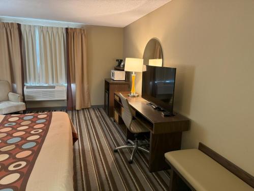 a hotel room with a bed and a desk with a television at Super 8 by Wyndham Winfield-Quail Ridge Area in Winfield