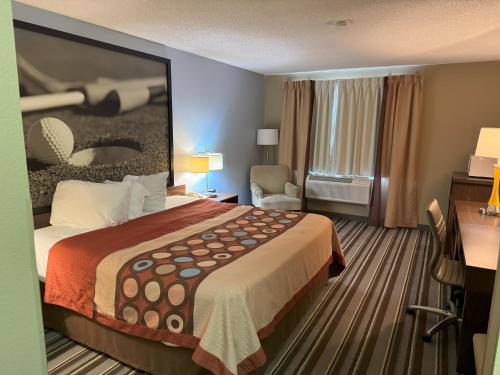 a hotel room with a large bed and a chair at Super 8 by Wyndham Winfield-Quail Ridge Area in Winfield