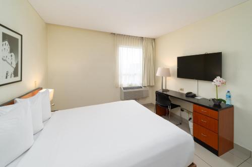 a bedroom with a bed and a desk with a television at Comfort Inn Real San Miguel in San Miguel
