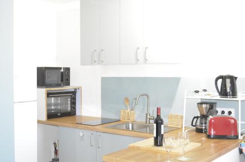 une cuisine blanche avec un évier et un micro-ondes dans l'établissement Amélia, à Soulac-sur-Mer