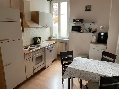 a kitchen with white appliances and a table with chairs at Holländers Apartment in Bruchsal