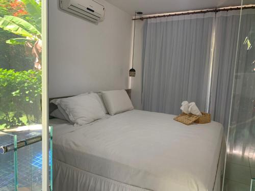 a white bed in a room with a window at Villas Supreme Apartamentos in Maceió