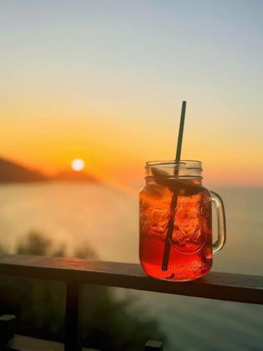 a mason jar with a straw sitting on a railing with the sunset at Dimora Rosetta - Appartamento panoramico a pochi minuti dalla spiaggia in SantʼAmbrogio