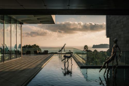 a building with a swimming pool with a view of the ocean at JW Marriott Jeju Resort & Spa in Seogwipo