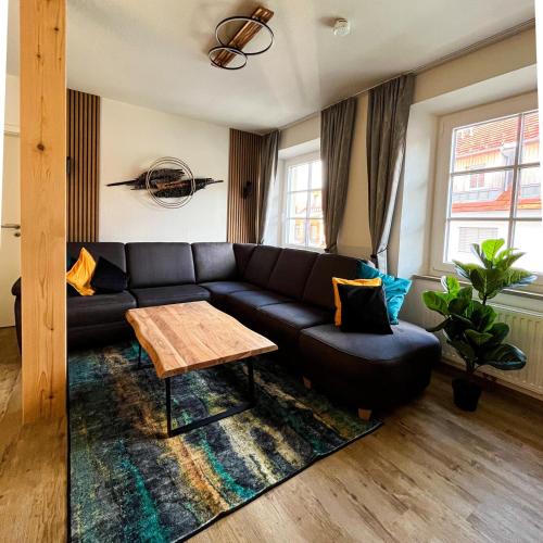 a living room with a black couch and a table at StayZen Holz & Hirsch Deluxe Hideaway zentral mit Parkplatz in Isny im Allgäu
