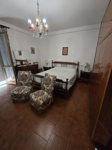 a bedroom with a bed and two chairs and a chandelier at Fiorucci Camere in Mocaiana