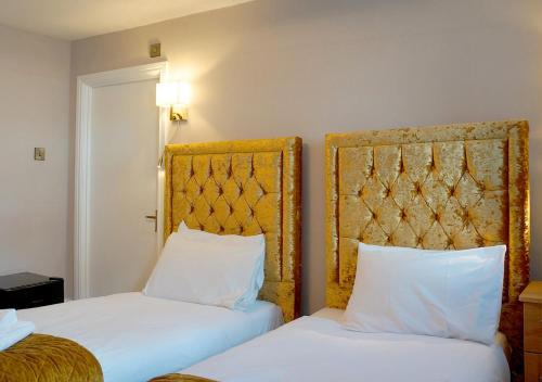 two beds with white pillows in a hotel room at The Pier Hotel in Eastbourne