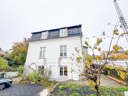 a white house with a car parked in front of it at Spacious and modern house close to Århus Center in Aarhus