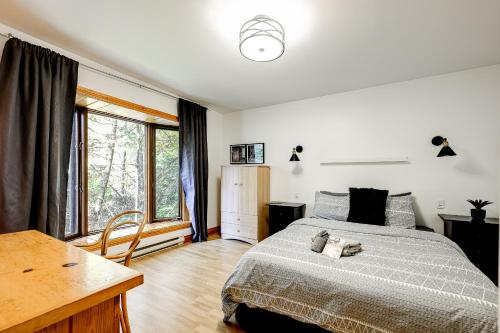 a bedroom with a bed and a desk and windows at Le Alesund, 5BR avec SPA, PLAGE et embarcations in Sainte-Lucie-de-Doncaster