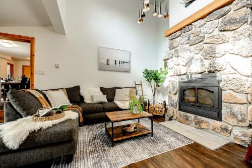 a living room with a couch and a stone fireplace at Le Alesund, 5BR avec SPA, PLAGE et embarcations in Sainte-Lucie-de-Doncaster