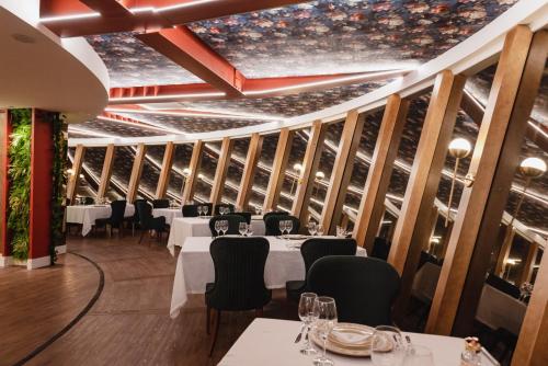 ein Esszimmer mit weißen Tischen und schwarzen Stühlen in der Unterkunft Hotel e Restaurante GIRATÓRIO RF Vision - A melhor vista 360 de Gramado in Gramado