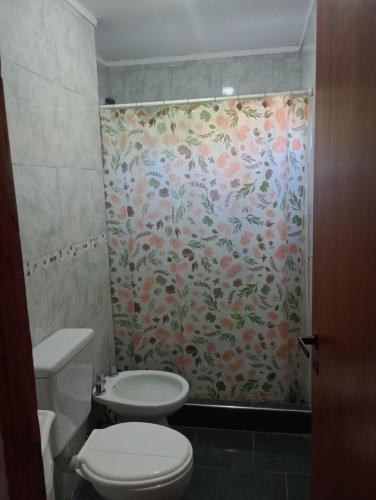 a bathroom with a toilet and a shower curtain at Departamentos Joaquin in Mar de Ajó