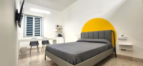 a bedroom with a bed with a yellow headboard at Casa Sunrise - The Guest House in Sciacca
