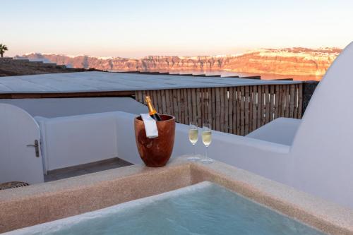 a swimming pool with two wine glasses and a bottle at Divino Caldera in Akrotiri