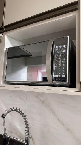 a microwave oven sitting on top of a counter at O melhor Apê da Região com Ar Cond, Wi-Fi e Hidromassagem in Brasilia