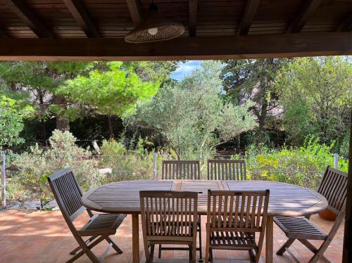 une table et des chaises en bois sur une terrasse dans l'établissement Maison 10 couchages, 5km des plages, 12km de Montpellier, à Pérols