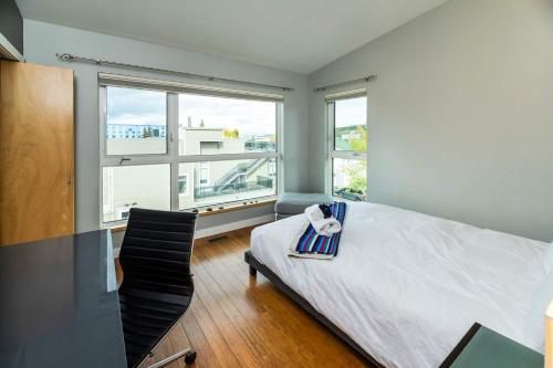 a bedroom with a bed and a chair and windows at NN - The Kit 4 - Downtown 1-Bed 1-Bath in Whitehorse