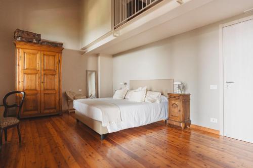 a bedroom with a white bed and a wooden floor at Tenuta Ronco Regio in San Fermo della Battaglia