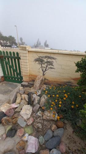a garden with rocks and a tree and a fence at Huisie Langs Die See in Swakopmund