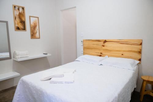 a bedroom with a white bed with a wooden headboard at Casa Natureza in Camaçari