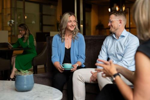a woman sitting on a couch talking to people at Sheraton Essen Hotel in Essen