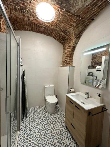 a bathroom with a white toilet and a sink at Entre Bóvedas in Cáceres