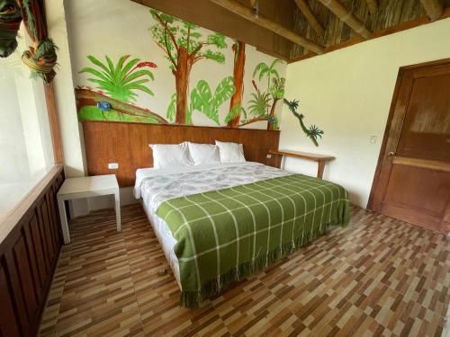 a bedroom with a bed with a painting on the wall at Biohostal Mindo Cloud Forest in Mindo