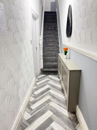 a hallway with a staircase with a vase of flowers at Wellesley Retreat 4BR Entire Home in Middlesbrough