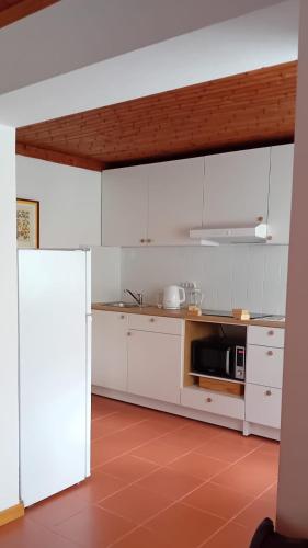 a kitchen with white cabinets and a microwave at Casa da Tília in Caxarias