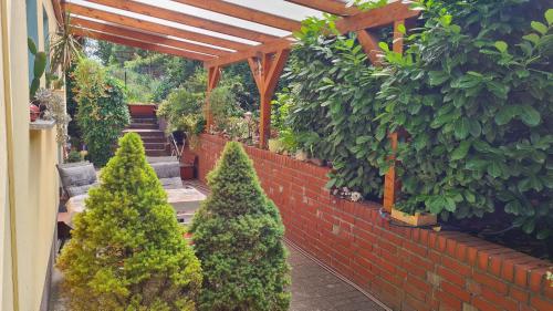 a group of trees in a garden with a brick wall at FeWo Arte in Wandlitz