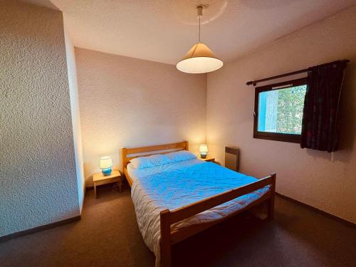 une chambre avec un lit avec une couette bleue et une fenêtre dans l'établissement Appartement 2 pièces avec terrasse à 200m des pistes, Autrans, 4 pers. - FR-1-737-19, à Autrans