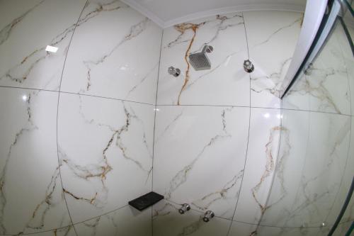 a bathroom with white marble walls and a shower at Hotel Maria da Fé in Aparecida
