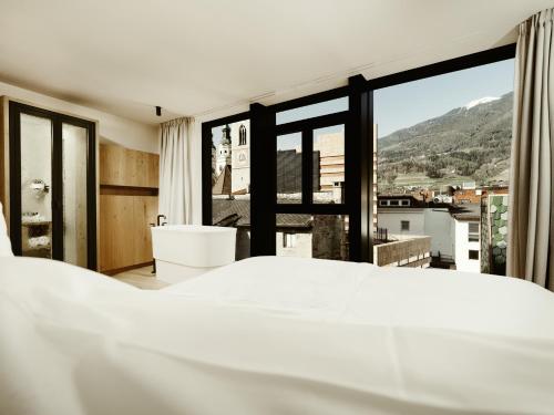 a bedroom with a bed and a large window at ADLER Historic Guesthouse in Bressanone