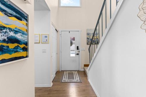 a hallway with white walls and stairs with paintings at Canandaigua Lake Retreat with view and private beach access, foliage, hike, and Ski in Canandaigua