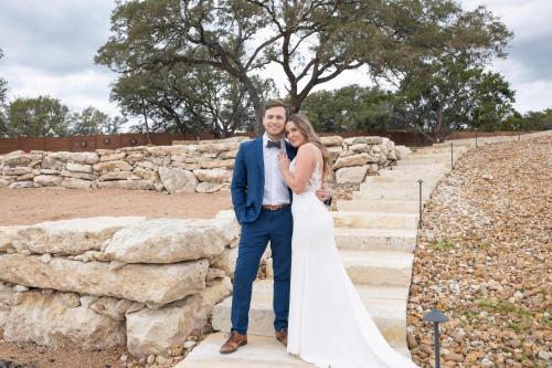 a bride and groom standing next to a stone wall at Starlight Horizon Cabin C - Pet-Friendly Texas Hill Country Cabin Near Canyon Lake - Pool, Stargazing & Group Getaways Sleeps 8 in Canyon Lake
