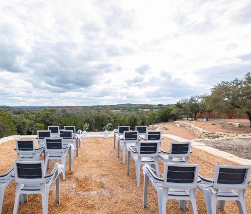 a row of white chairs sitting on top of a field at Starlight Horizon Cabin C - Pet-Friendly Texas Hill Country Cabin Near Canyon Lake - Pool, Stargazing & Group Getaways Sleeps 8 in Canyon Lake