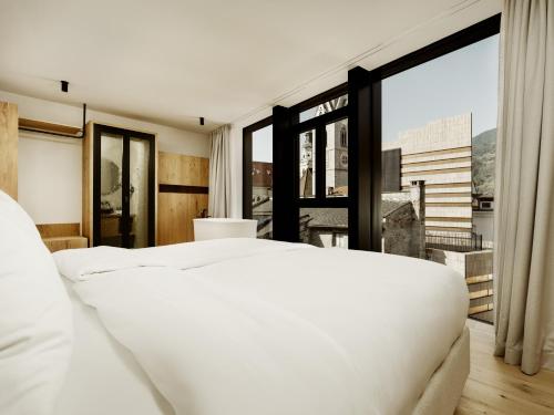 a bedroom with a white bed and a large window at ADLER Historic Guesthouse in Bressanone