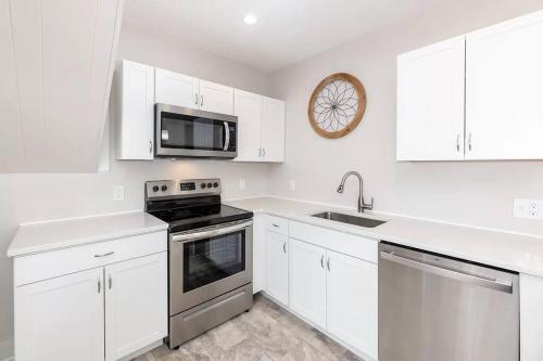 a kitchen with white cabinets and a stove and a microwave at 2-Unit House, big Lake Winnisquam views - Sleeps 13 in Tilton