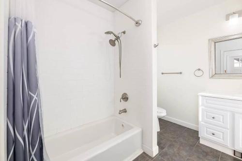 a white bathroom with a tub and a sink at 2-Unit House, big Lake Winnisquam views - Sleeps 13 in Tilton