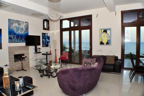 a living room with a purple chair and a couch at Beach Villa Pantheon in Pomos
